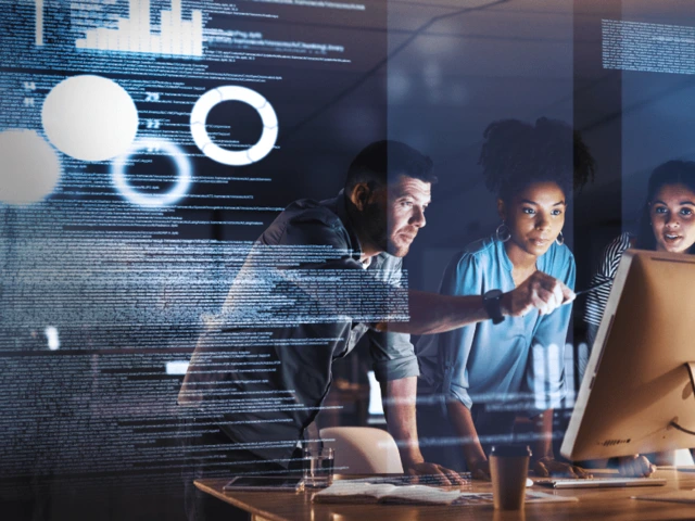three people gathered around a computer monitor