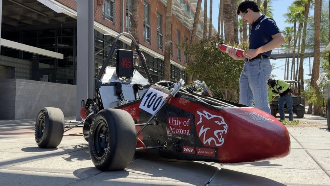 An engineering student stands by the Wildcat Formula Racing club's "WF25" vehicle on the University of Arizona campus.
