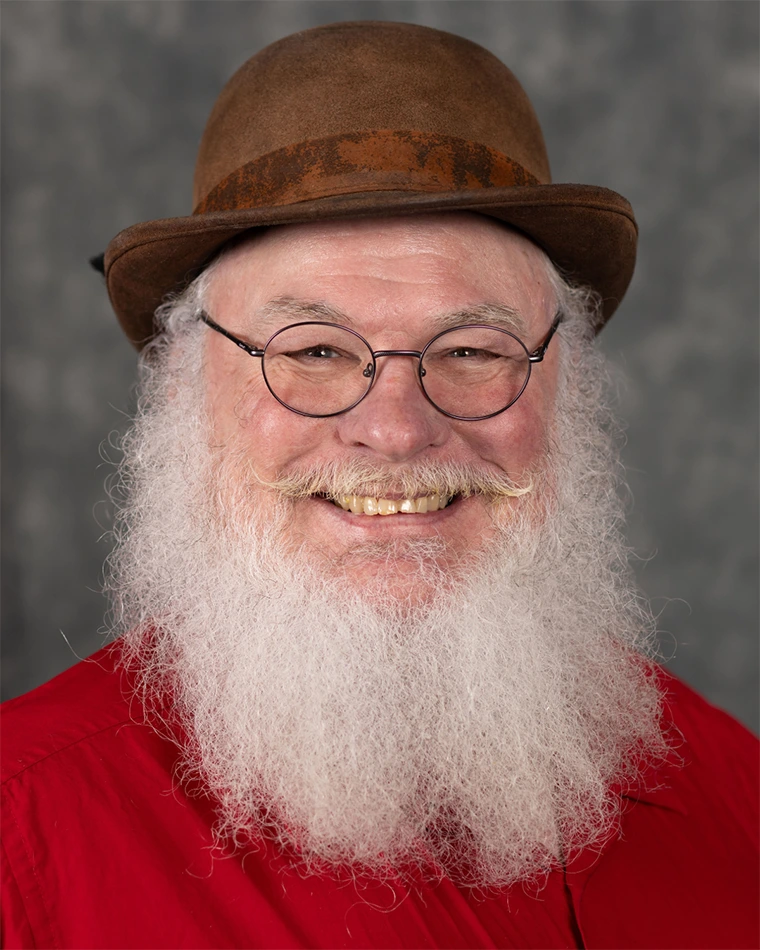 headshot of person with white beard, wearing glasses and brown hat