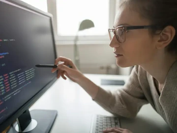 person wearing glasses, pointing a computer screen