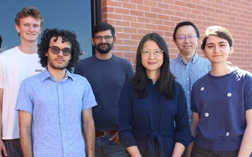 group of people standing in front of window and brick wall